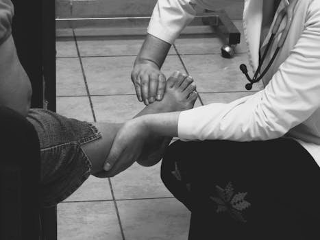 pexels-photo-33934620-33934620 Doctor examines a patient's foot during a medical consultation in a clinic setting.